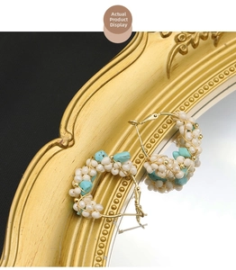 Detail showing handcrafted gold wire wrapped pearl and turquoise hoop earrings on mirror