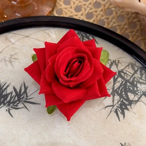 Close-up of velvet red rose hair clip with green leaves on traditional ink bamboo plate