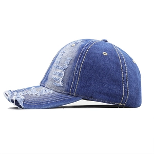 Close-up of distressed denim baseball cap with vintage frayed holes and stitched details