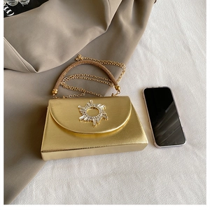 Detail of gold evening clutch featuring a rhinestone ring buckle and crystal handle