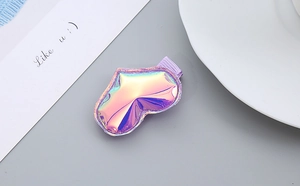 Detail of holographic heart and lip hair clip on a purple base with a minimalist backdrop