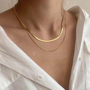 Three-layer gold snake bone necklace in stainless steel on a model wearing white