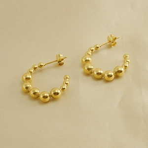 18K gold plated stainless steel C-shaped beaded hoop earrings on beige silk fabric