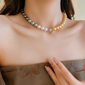 Detailed close-up of a three-color pearl necklace with gold, white, and black pearls