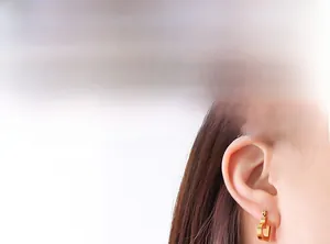Close-up of minimalist gold heart-shaped earrings worn on model for style display