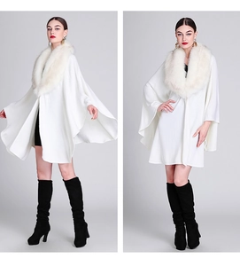 Detail of white knitted cape with faux fox fur collar and elegant draping silhouette