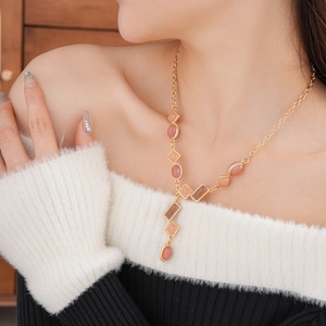 Detail of vintage gold Y-necklace with peach gemstones and diamonds on a model