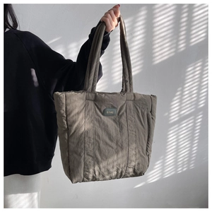 Detailed view of dark khaki nylon tote bag with puffer texture and oval logo on the front
