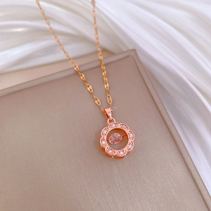 Macro shot of rose gold flower necklace with pink gemstone on beige jewelry box