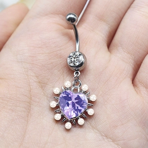 Close-up of silver navel ring with purple heart gemstone and white pearl border