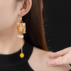 Detail of vintage gold flower earrings with tassels and white pearls on a female model