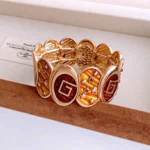 Macro detail of vintage gold elastic bracelet with red enamel G-logo and star pattern