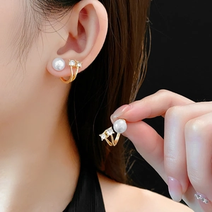 Détail macro de boucles d'oreilles perles et cristaux avec finition dorée sur fond noir