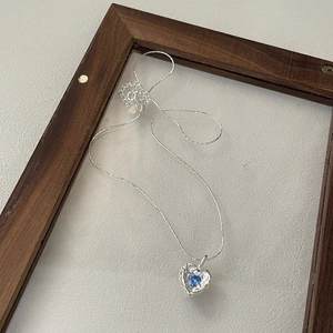 S925 sterling silver heart necklace with blue zircon on a rustic wooden background