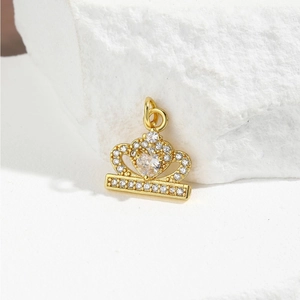 Detailed view of a golden crown pendant with heart-shaped stone on a white stone base