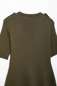 Macro detail of dark green rib-knit dress with decorative shoulder flap and V-neckline