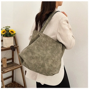 Detail of vintage olive green tote bag showing distressed leather texture and stitching