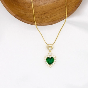 Macro shot of a gold heart-shaped emerald pendant necklace with inlaid diamonds detail