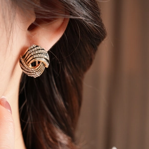Gros plan de boucles d'oreilles vintage dorées avec strass brillants et émail noir