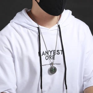 Detail of men's stainless steel compass pendant necklace worn over a white hoodie