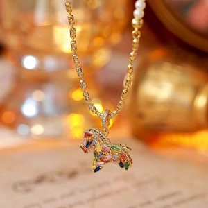 Vista macro di una collana a forma di pony dorato con zirconi colorati su sfondo sfocato