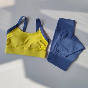 Flat lay of yellow and navy blue high-stretch yoga set with natural sunlight shadows