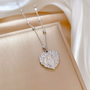 Detail shot of silver heart pendant with MOM engraving and gemstone on silk