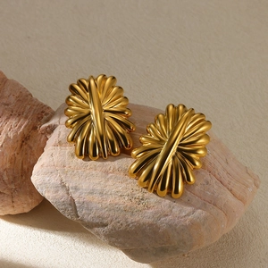 Detail view of gold-plated stainless steel fan-shaped stud earrings on natural stone