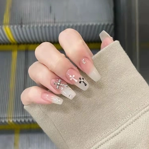 Detailed view of long coffin press-on nails with nude gradient and silver gothic crosses