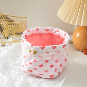 Pink quilted fabric storage basket with red heart patterns and white lace trim