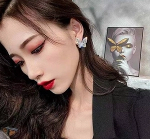 Detail of silver hollow butterfly stud earring with sparkling cubic zirconia on model