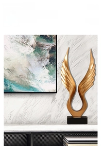 Detail of matte gold angel wing sculpture with a black base for modern home decor