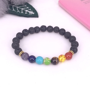 Vista macro de pulsera de energía 7 Chakra con piedra de lava y anillos dorados sobre blanco