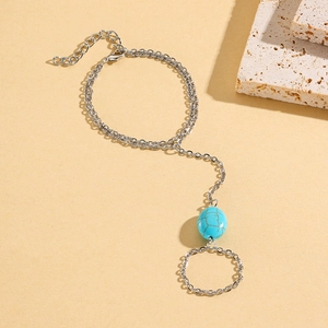 Detail of silver hand chain featuring turquoise bead and layered connection rings