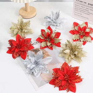 Flat lay of red and gold glitter poinsettia flowers on a white Nordic style desktop