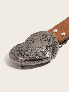 Detail of heart-shaped silver buckle with floral carvings on brown textured leather belt