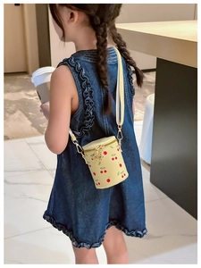 Detail of girl's cherry print bucket bag showing adjustable strap and gold hardware