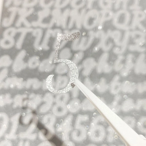 Self-adhesive 1-inch silver glitter number 5 sticker held by tweezers for DIY crafts