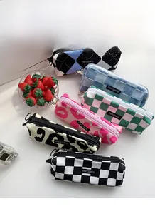 Close-up of checkered and leopard print canvas pencil cases with metal zippers