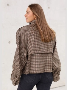 Detail of a brown houndstooth wool short jacket featuring back storm flap and sleeve straps