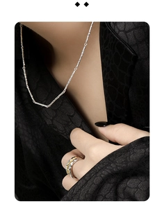 Detailed macro view of S925 silver necklace and dual-tone textured ring on black fabric