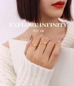 Detail of 18K gold-plated arrow and heart open ring worn by a model in lifestyle setting