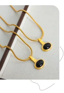 Detail view of retro oval black glass pendant on gold plated snake chain necklace