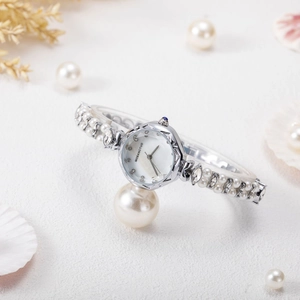 Detail of luxury women's watch with pearl bracelet strap and mother-of-pearl dial texture