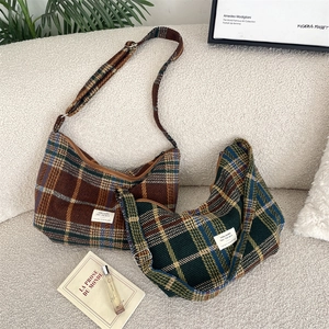 Close-up of retro plaid crossbody bags in brown and green on a soft fabric surface
