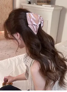 Détail d'une pince à cheveux en satin rose clair avec ornement doré sur modèle