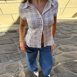 Detail of light coffee plaid short sleeve shirt and wide leg denim jeans on outdoor model
