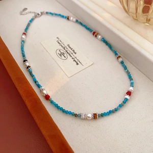Detail of handmade beaded necklace with sky blue beads and white pearls on a tray
