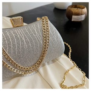 Detail of silver glitter evening bag with gold chain strap and diamond buckle closure
