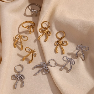 Close-up of gold and silver bow jewelry set with zircon accents on silk background
